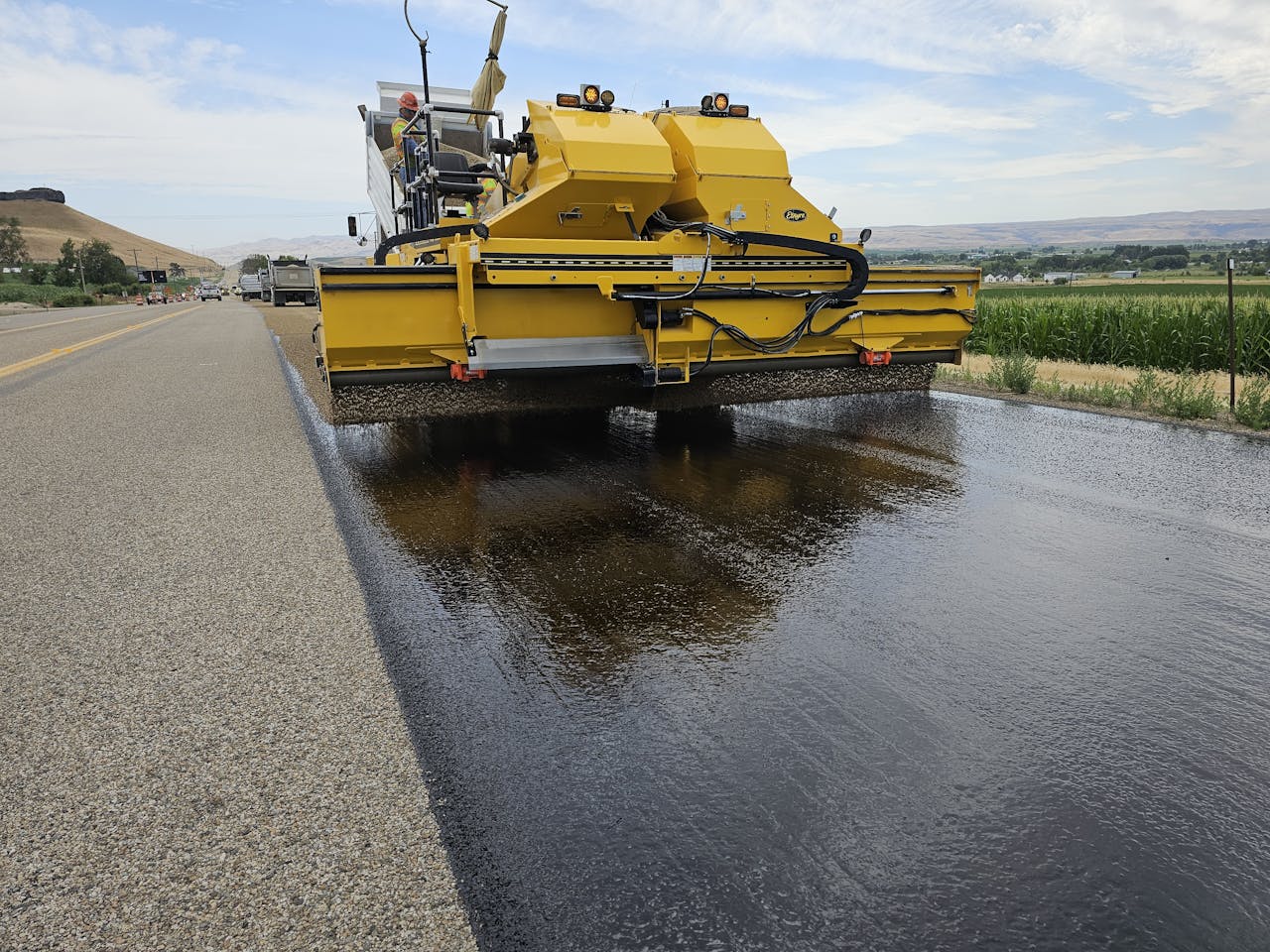 Yellow road construction machine applying asphalt on a rural road in Marsing, Idaho.